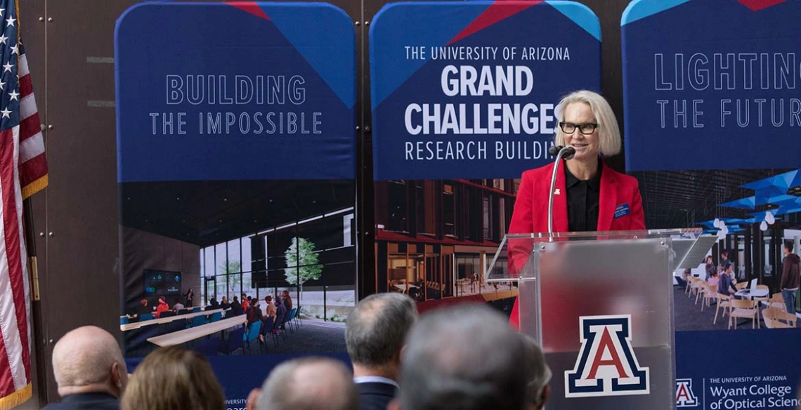 Betsy Cantwell stands at a podium in front of a crowd