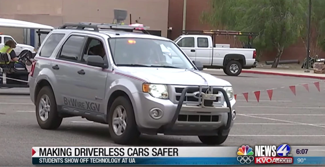 Screencap of a newscast with a car driving across the frame and a lower-third caption that reads, "Making Driverless Cars Safer: Students Show Off Technology at UA"