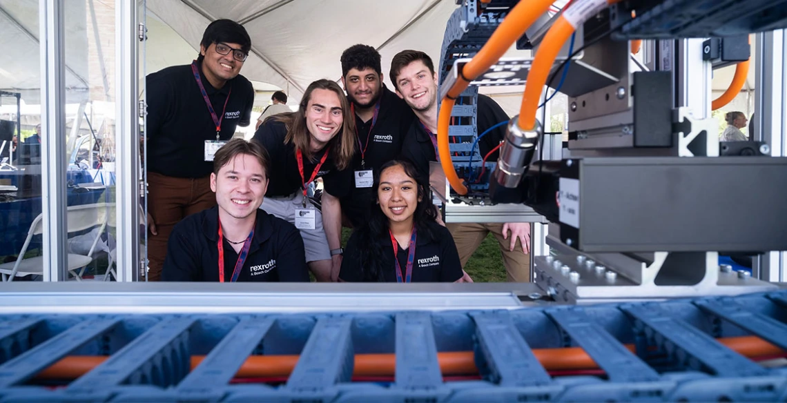 6 students pose with a manufacturing device