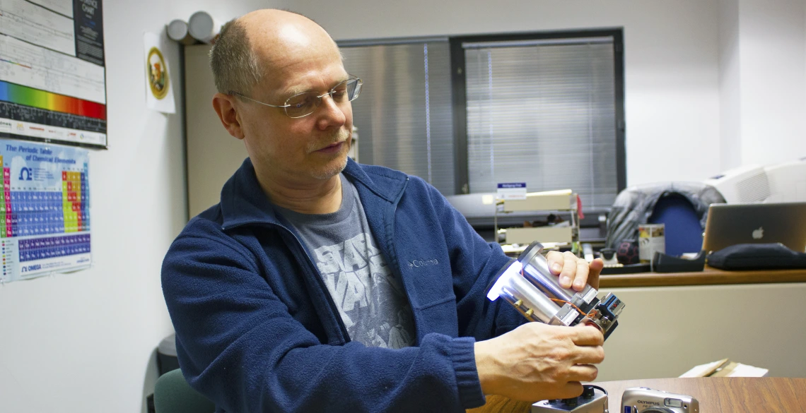 Wolfgang Fink holding up a metal, binocular-like device.