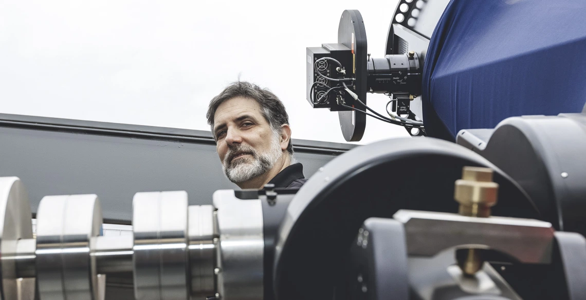 Roberto Furfaro standing behind a telescope