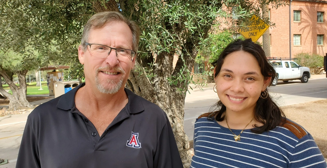 Greg Ogden and Carla Colon Cruz smile for a photo. They are outside in front of a tree.