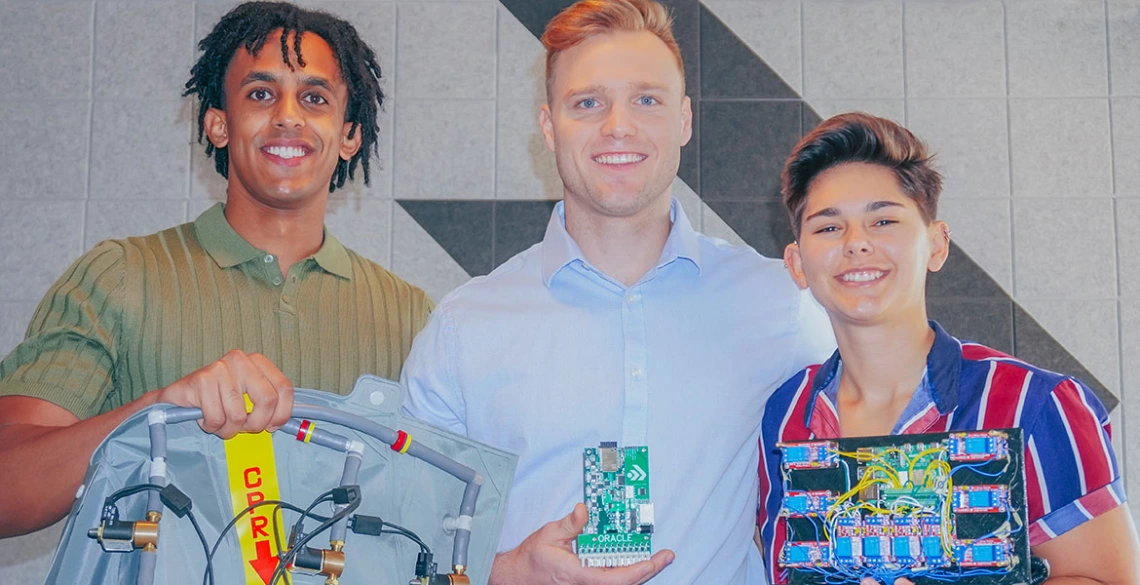 three people pose with computer parts