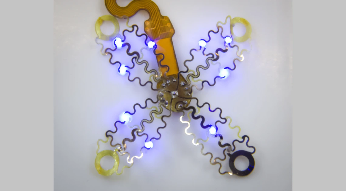 a device that looks like metallic mesh has four petal like pieces radiating from the middle. it is lit up with small blue lights.