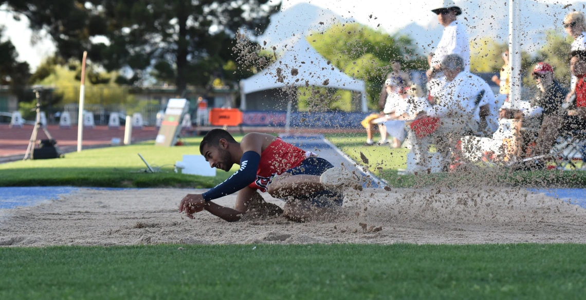 Mo Almarhoun sliding in the dirt after completing a long jump.