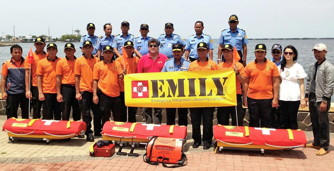 a large group of people pose near water with rescue equipment