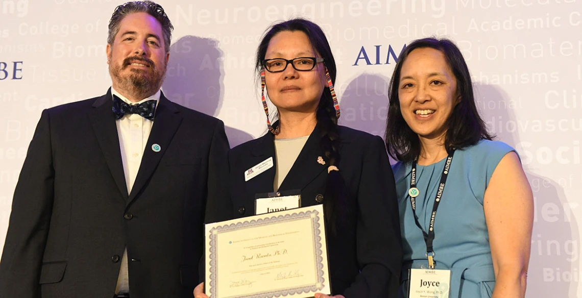 Three people pose with an award certificate