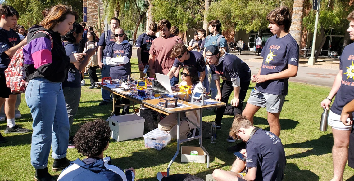 Students group around a table holding solar trackers