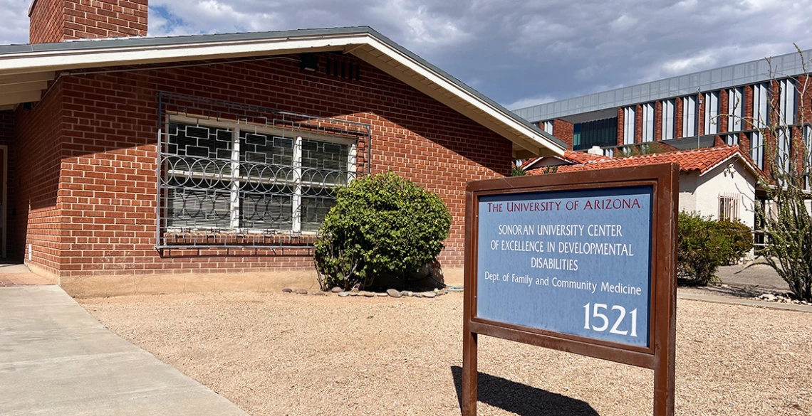 A red brick building is pictured with a blue sign in the front.