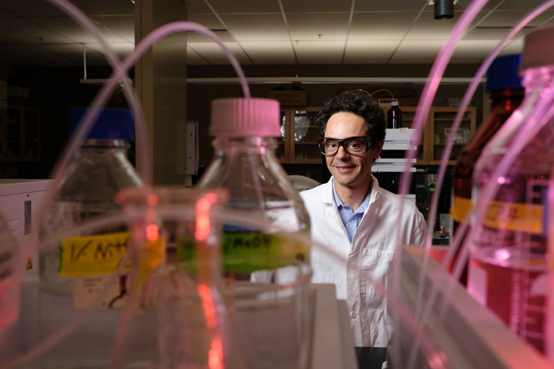 Andrea Achilli in his lab, with beakers in the foreground of the photo.