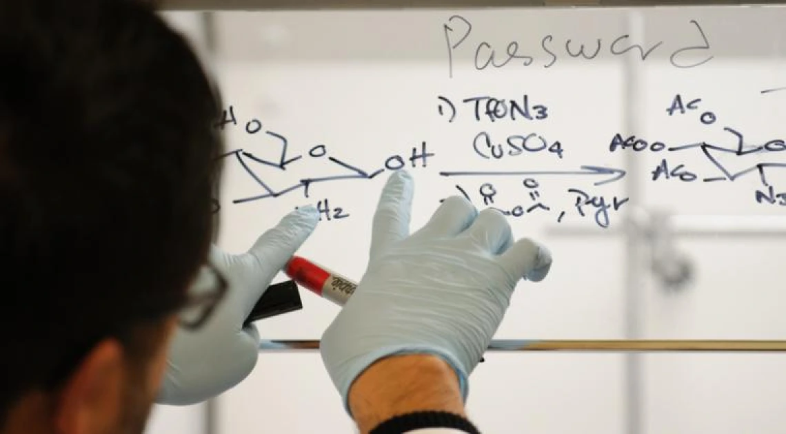 A man writing in marker on a window.