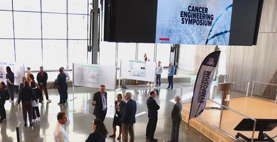 A small crowd of people in a large room with scientific poster displays