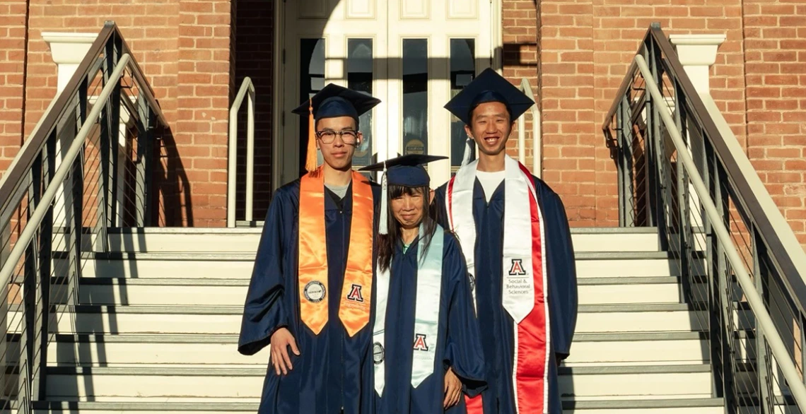 Three people pose on the steps of Old Main at the University of Arizona