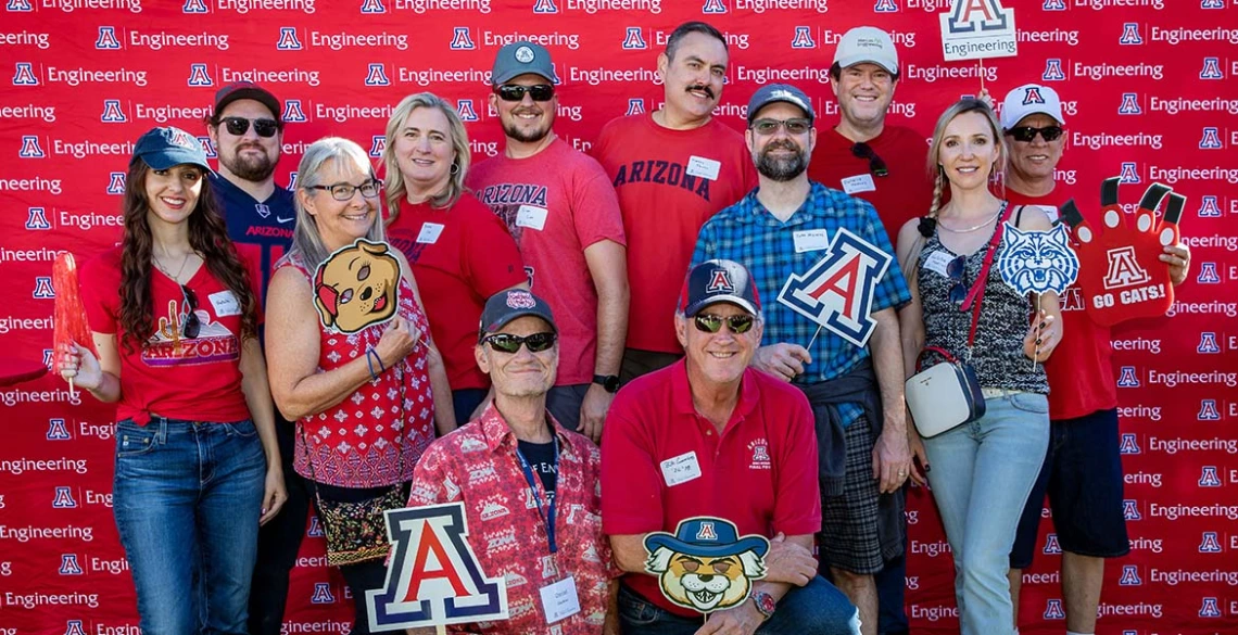 a group of people poses in front of a backdrop at the Homecoming tailgate