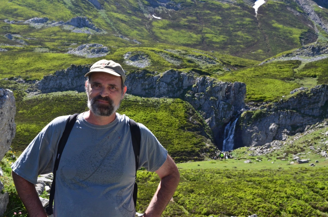 Jim Field on a hike smiling with a green landscape behind him