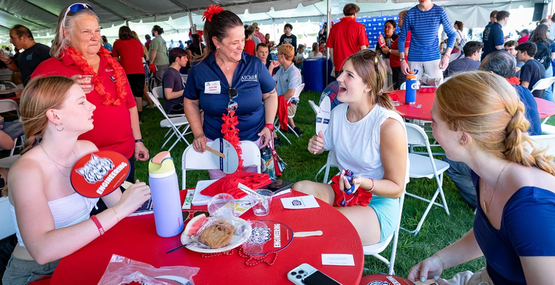 a group of students and faculty at an event table