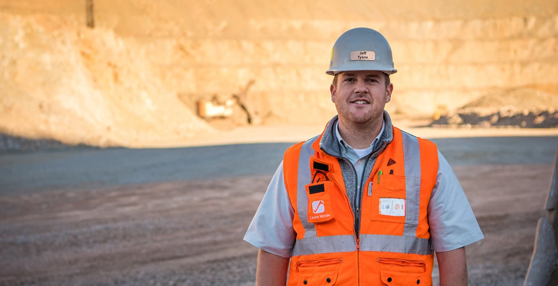 UA mining engineering alumnus Jeff Tysoe stands at the bottom of an open pit mine in a hardhat and orange safety vest