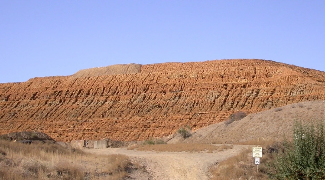 A pile of mine tailings against a blue sky.