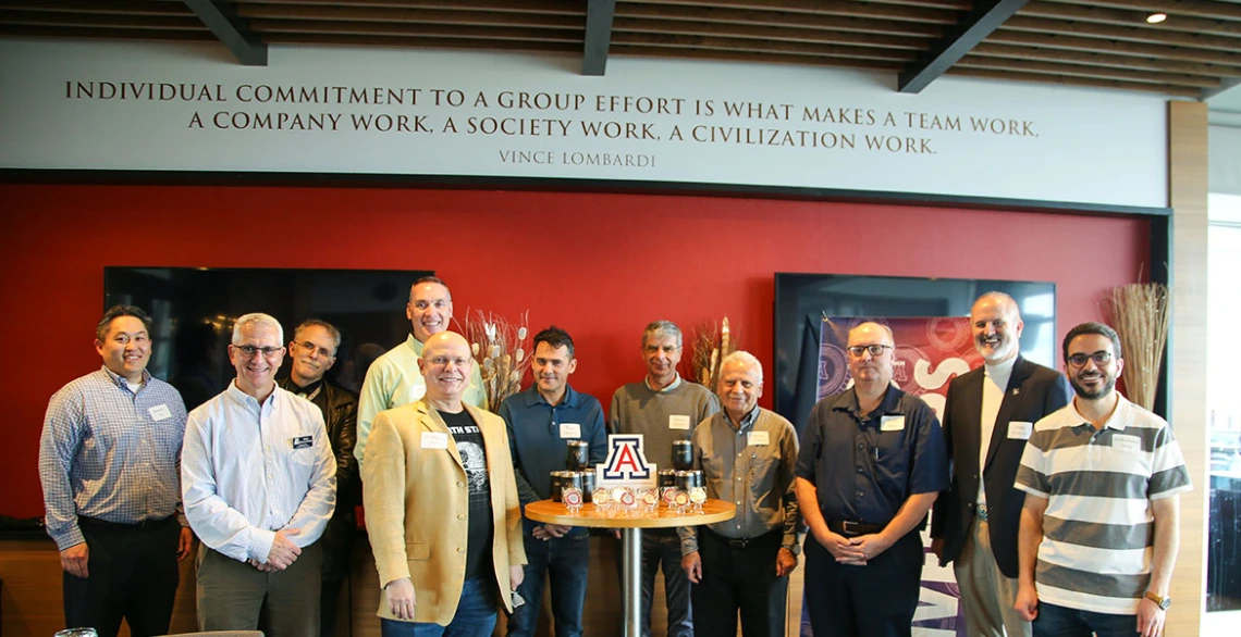 A group of 11 stands around a table holding award medallions