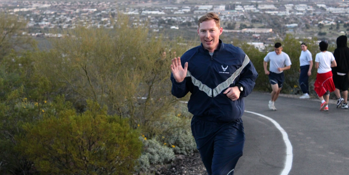 Ryan Raettig smiling and waving as he runs up Tumamoc Hill.