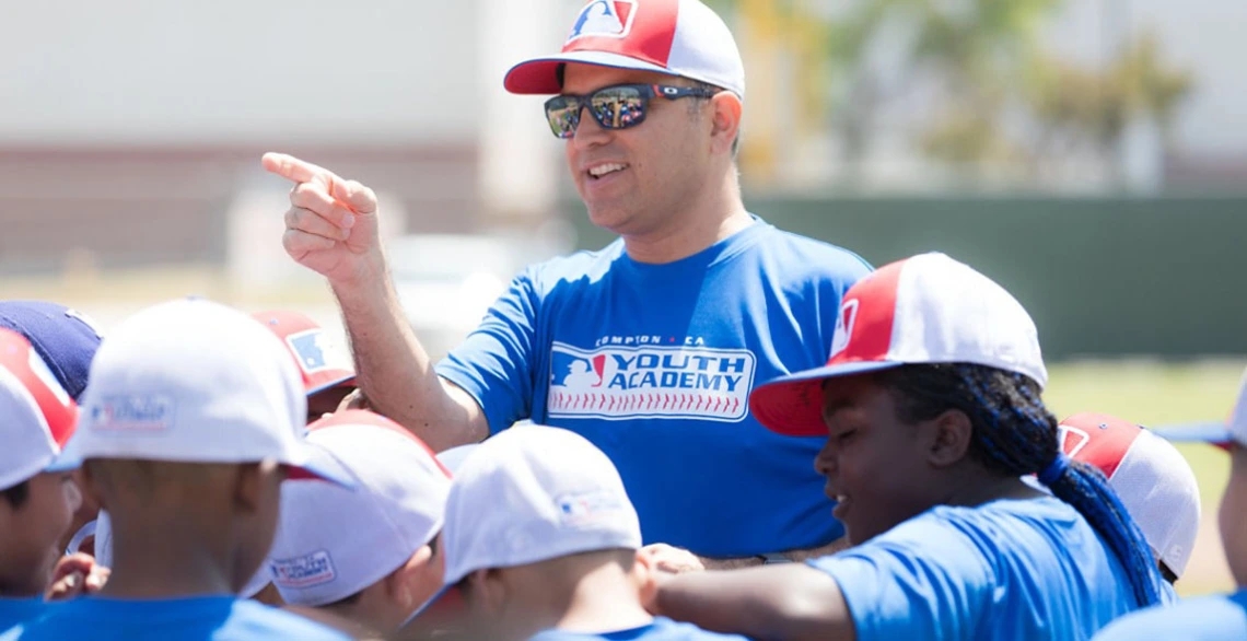 Ricardo Valerdi addresses a group of children in baseball caps outdoors