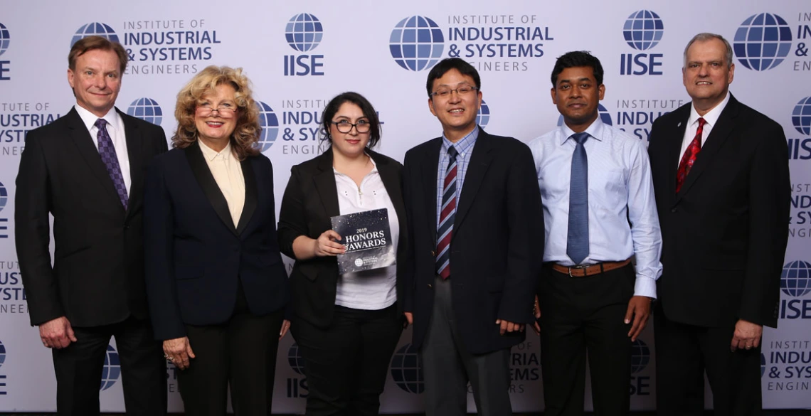 Six professionals pose for a photo in front of an IISE backdrop.