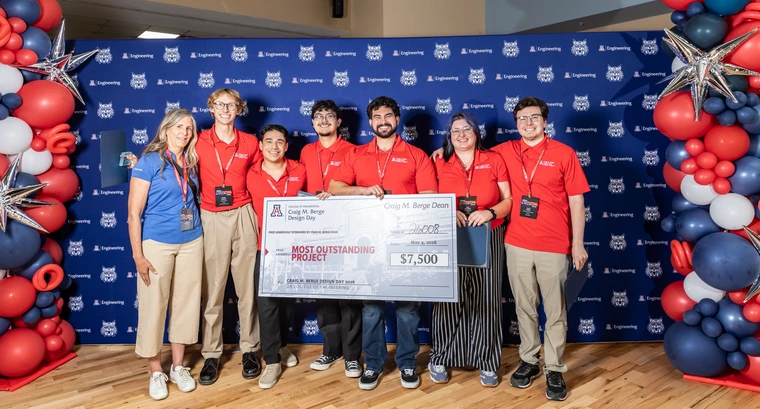 Six people in red shirts hold a large check.