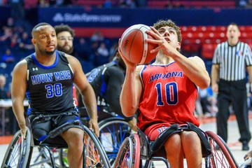 Two men in wheelchairs play basketball.