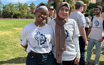 two students stand in a grassy field