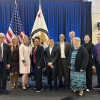 10 people pose in front of American and patent office flags