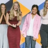 Six people on a stage react to winning an award.