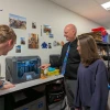 Three people surround a piece of equipment in a classroom