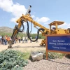 A yellow mining shovel vehicle sits behind a blue sign.