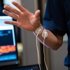 A man in a blue polo demonstrates a medical device on his wrist.