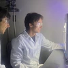 Two students with dark hair look at a 3D printer.