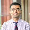 A man in a patterned tie smiles at the camera.