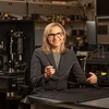 A woman with blond hair holds up a really tiny microscope.