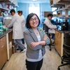A woman in a grey jacket poses for a photo in a lab.