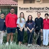 Students and a dentist take a photo outside of a dental office.