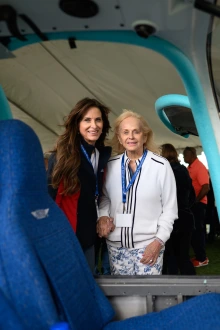 A woman with brown hair and a woman with grey hair look at an airplane.