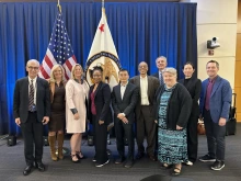 10 people pose in front of American and patent office flags