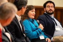 Three fellow panelists listen to Dawn Wellman, speaking with a microphone.
