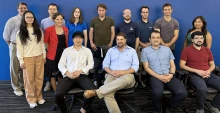 A group of instructors poses indoors, with one row sitting and one standing