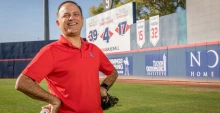 Ricardo Valerdi stands with a baseball and catcher's mitt in a baseball stadium