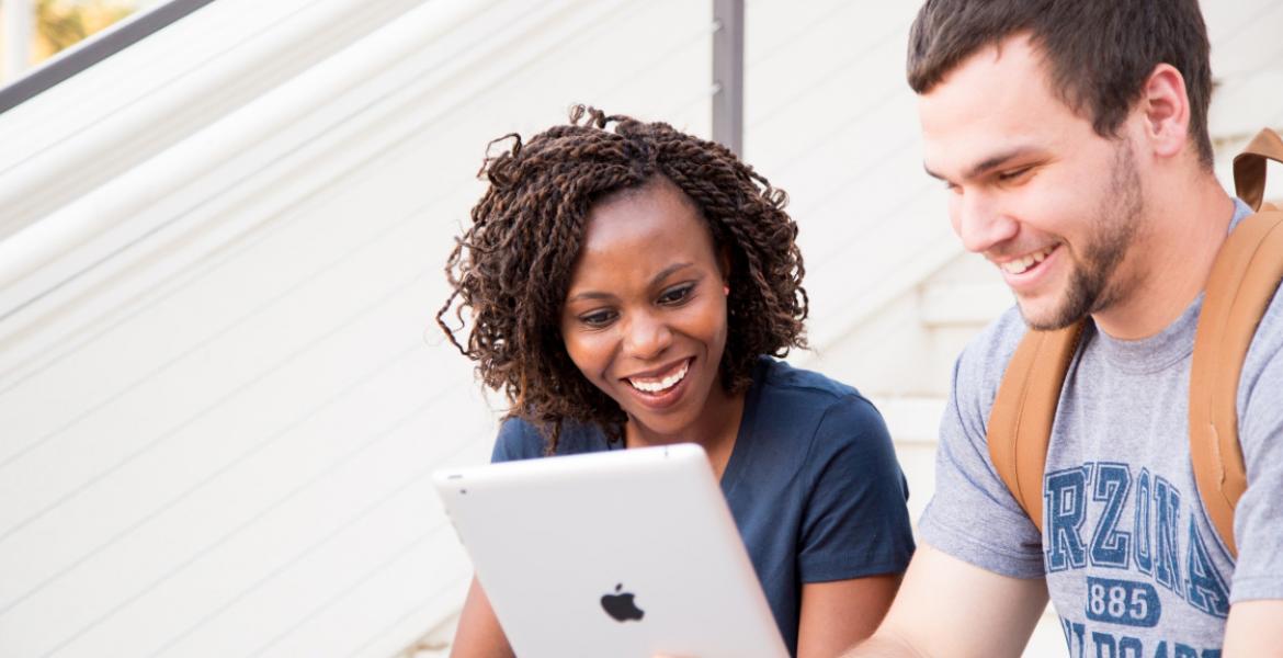 two students look at a laptop