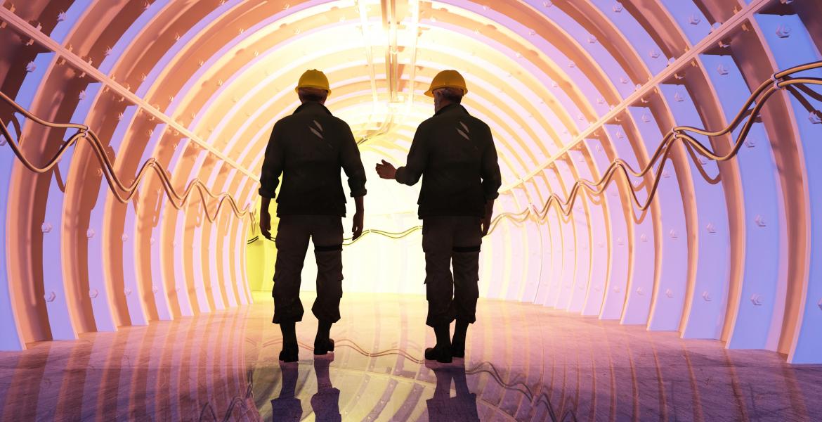 Two men walking down a tunnel. They are silhouetted agains a purple-ish light coming from the end of the tunnel.
