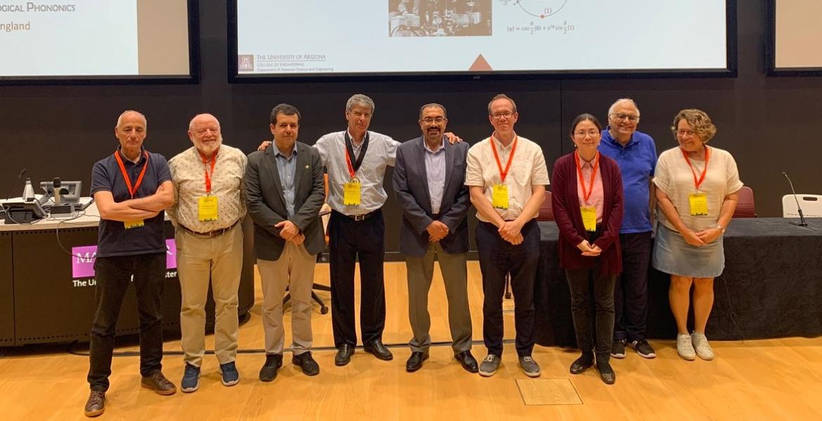 Nine people, most of whom are wearing conference lanyards, pose for a photo.