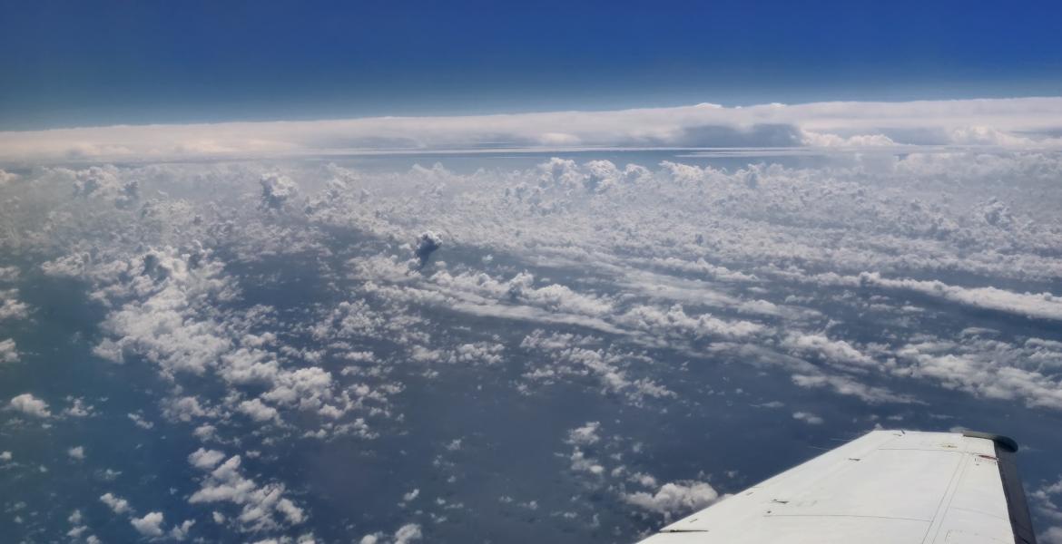 A photo of the top of the cloud layer, taken from a plane. The wing of the plane is visible in the bottom right of the photo.