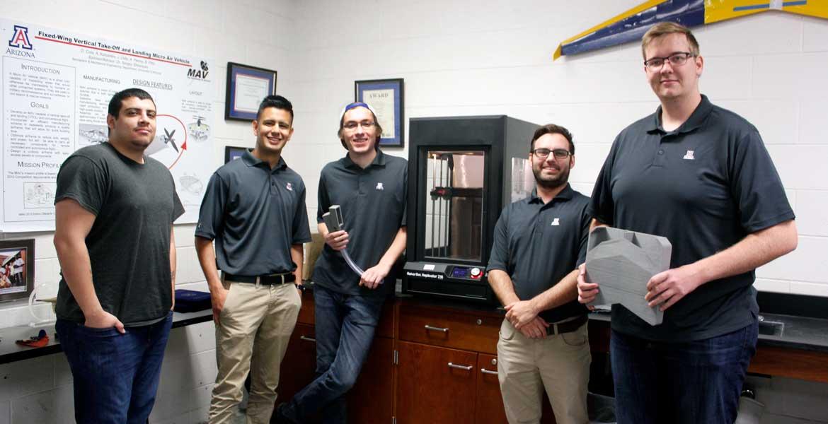 Five students standing by a 3D printer