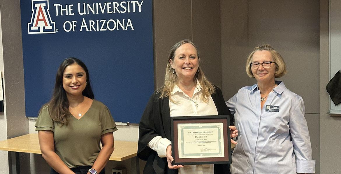 Three people pose with an award certificate